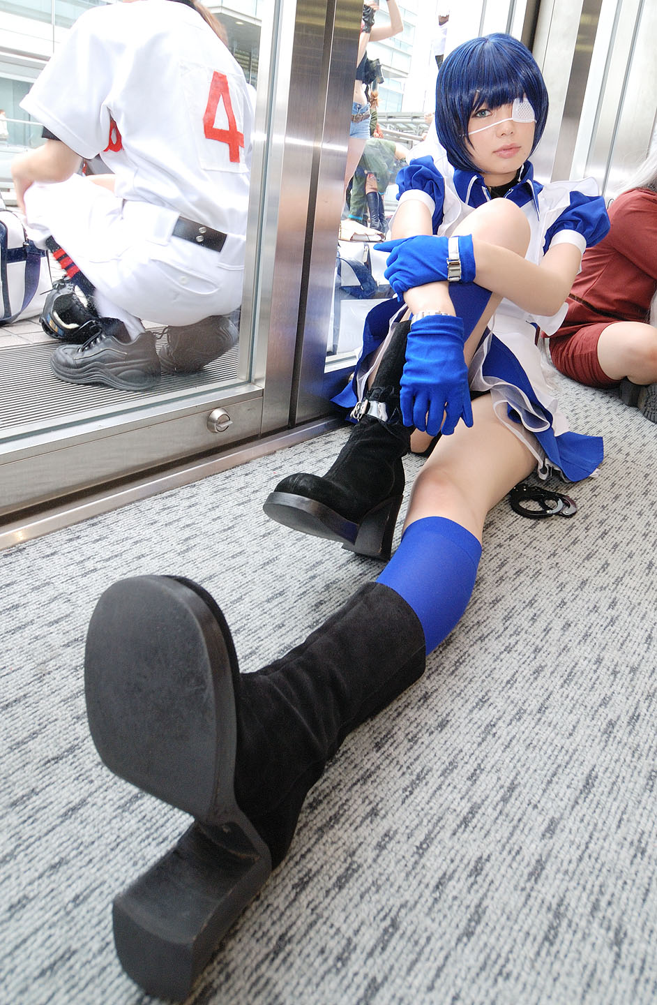 namada, ryomou shimei, ikkitousen, black footwear, highres, photo (medium), 1girl, apron, asian, blue eyes, blue gloves, blue hair, blue socks, blurry, boots, collar, color contacts, cosplay, cross, cuffs, depth of field, dutch angle, eyepatch, gloves, handcuffs, high heels, hugging own legs, indoors, kneehighs, looking at viewer, maid, maid apron, on floor, panties, pantyshot, puffy short sleeves, puffy sleeves, reflection, ryomou shimei (cosplay), short sleeves, sitting, socks, solo focus, underwear, upskirt
