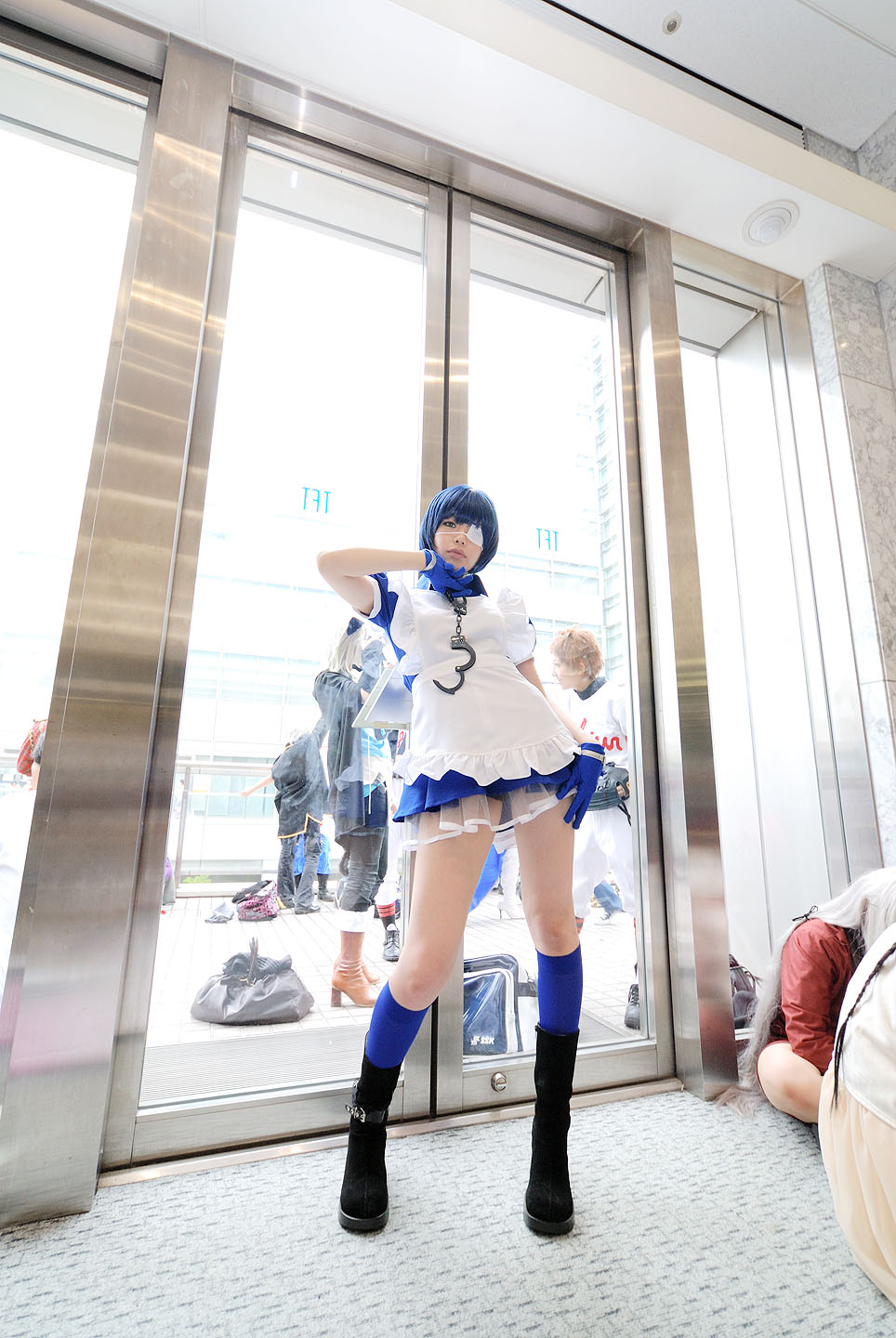 namada, ryomou shimei, ikkitousen, black footwear, highres, photo (medium), 1girl, apron, asian, blue eyes, blue gloves, blue hair, blue socks, boots, collar, color contacts, contrapposto, cosplay, cross, cuffs, eyepatch, full body, gloves, handcuffs, high heels, indoors, kneehighs, looking at viewer, maid, maid apron, puffy short sleeves, puffy sleeves, ryomou shimei (cosplay), short sleeves, socks, solo focus, standing