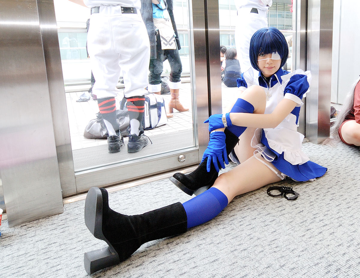 namada, ryomou shimei, ikkitousen, black footwear, photo (medium), 1girl, apron, asian, blue eyes, blue gloves, blue hair, blue socks, boots, collar, color contacts, cosplay, cross, cuffs, dutch angle, eyepatch, gloves, handcuffs, high heels, hugging own legs, indoors, kneehighs, looking at viewer, maid, maid apron, on floor, puffy short sleeves, puffy sleeves, reflection, ryomou shimei (cosplay), short sleeves, sitting, socks, solo focus