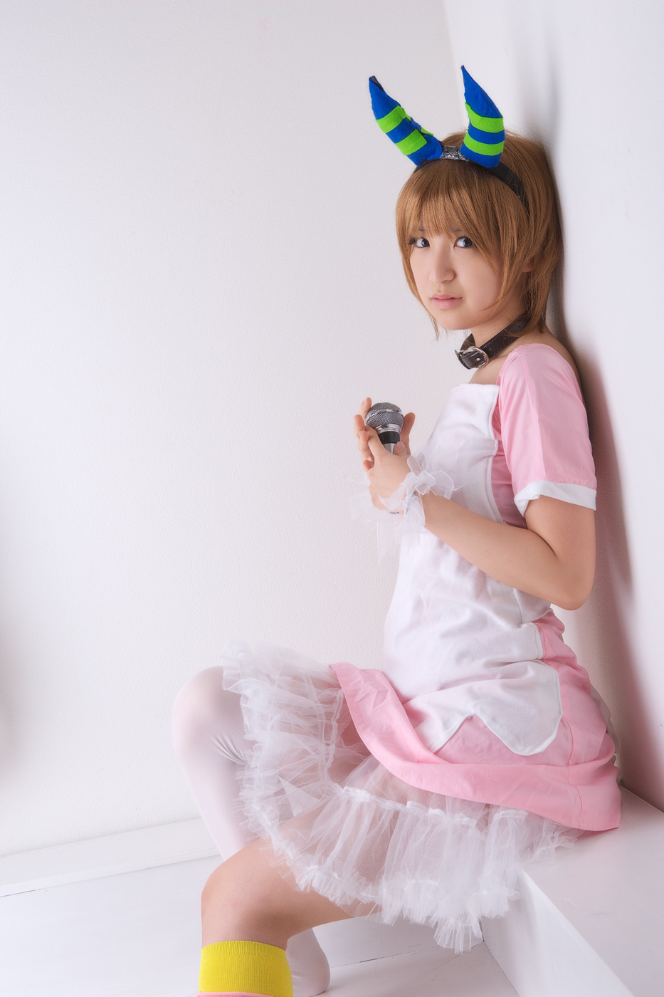 richi, linda (boku to maou), boku to maou, striped, highres, photo (medium), against wall, apron, brown hair, collar, cosplay, dress, flat chest, hairband, horns, kneehighs, lipstick, makeup, microphone, pink lips, see-through clothes, shadow, short hair, single kneehigh, single sock, single thighhigh, sitting, socks, solo, thighhighs, white socks, wristband