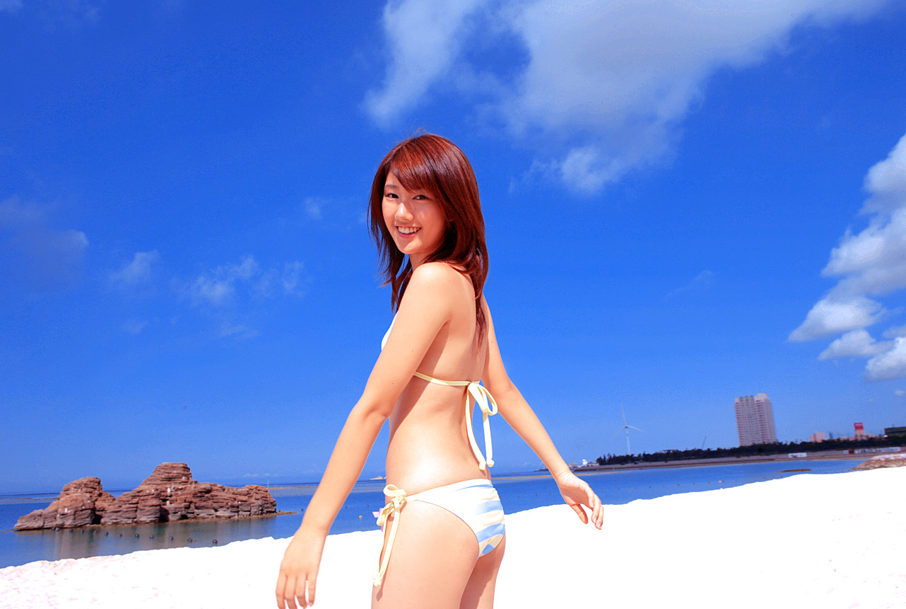 takigawa hanako, photo (medium), 1girl, asian, beach, bikini, blurry, breasts, cloud, cowboy shot, depth of field, dutch angle, female focus, japanese (nationality), long hair, looking at viewer, ocean, outdoors, side-tie bikini bottom, sky, small breasts, smile, solo, standing, striped bikini, striped clothes, swimsuit