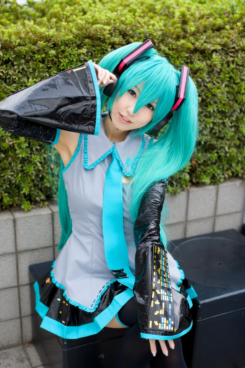 arusagawa sakura, hatsune miku, vocaloid, cosplay photo, highres, photo (medium), 1girl, aqua hair, aqua necktie, armpits, black thighhighs, blouse, collared shirt, cosplay, detached sleeves, dress, female focus, fingernails, frilled shirt, frills, grey shirt, hair between eyes, head tilt, long fingernails, microphone, necktie, sailor, school uniform, serafuku, shirt, sleeveless, sleeveless shirt, solo, thighhighs, twintails