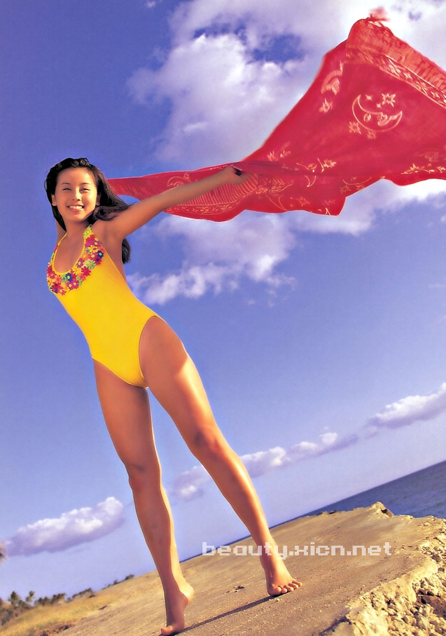 highres, photo (medium), 1girl, asian, barefoot, beach, beach towel, black hair, breasts, cloud, grin, holding, japanese (nationality), long hair, medium breasts, ocean, one-piece swimsuit, sand, sky, smile, standing, swimsuit, teeth, towel, water, yellow one-piece swimsuit