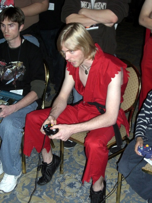 ken masters, capcom, nintendo, street fighter, cosplay photo, photo (medium), 2boys, arm hair, beard, black hair, blonde hair, chair, controller, cosplay, crossed arms, denim, facial hair, game console, game controller, gamecube, hairy legs, japanese clothes, jeans, jewelry, ken masters (cosplay), leaning forward, male focus, multiple boys, necklace, pants, pectorals, pendant, sash, shirt, shoes, short hair, sitting, sleeveless, sleeves rolled up, sneakers, striped clothes, striped shirt, torn clothes