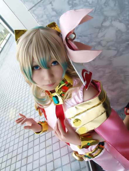 nia teppelin, tengen toppa gurren lagann, cosplay photo, photo (medium), 1girl, bare shoulders, blonde hair, blue eyes, blue hair, bow, bracelet, closed mouth, collar, cosplay, dress, dutch angle, female focus, flower, gradient hair, hair bow, hair flower, hair ornament, hand on own chest, head tilt, indoors, jewelry, kneeling, lips, long hair, looking at viewer, multicolored hair, necktie, pink dress, red necktie, sleeveless, sleeveless dress, solo, tile floor, tiles, yellow bow