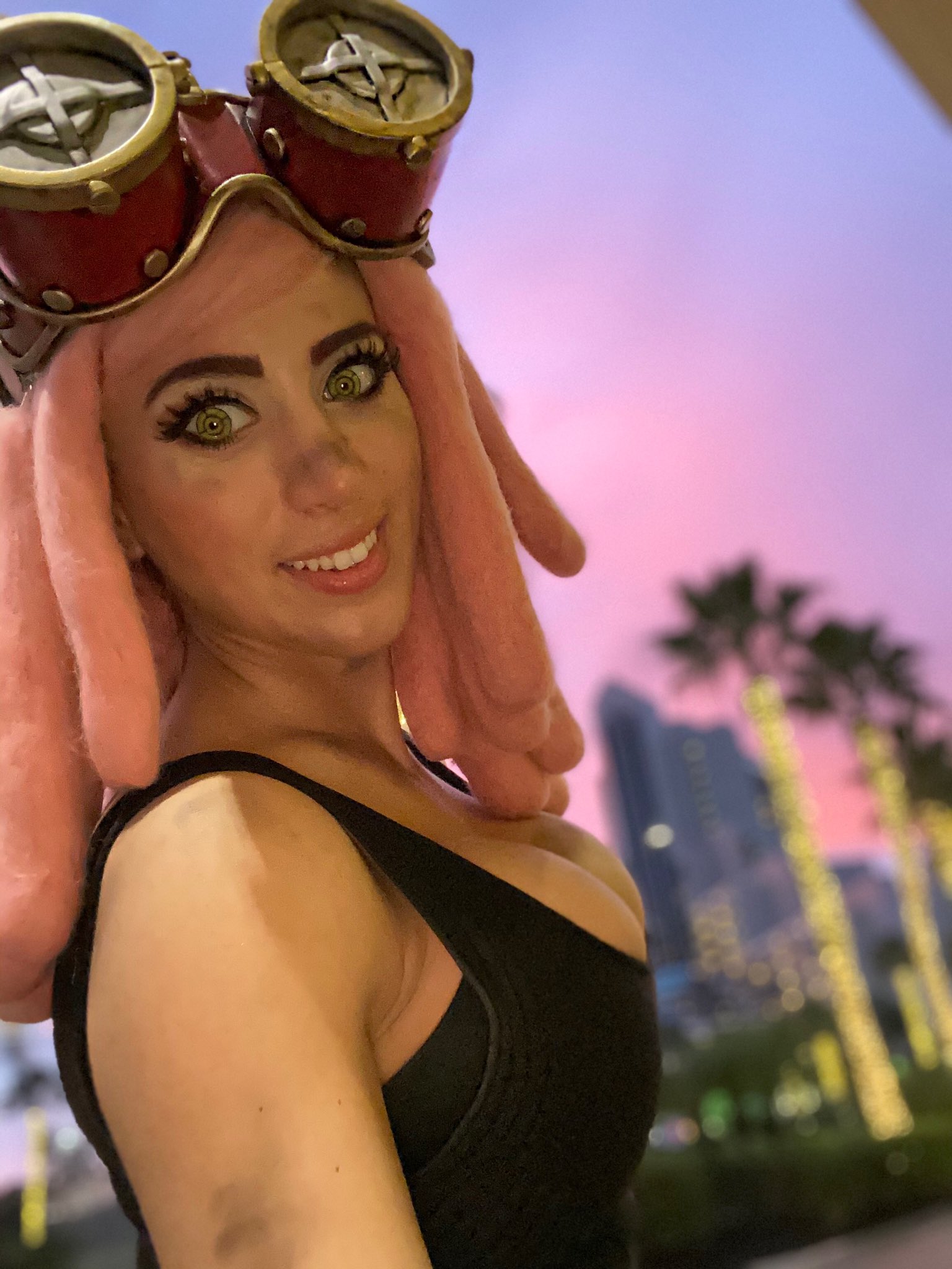 elizabeth rage, hatsume mei, boku no hero academia, real life, cosplay photo, highres, photo (medium), 1girl, bare shoulders, black tank top, breasts, cleavage, cosplay, female focus, goggles, goggles on head, hatsume mei (cosplay), large breasts, looking at viewer, pink hair, solo, tank top, yellow eyes