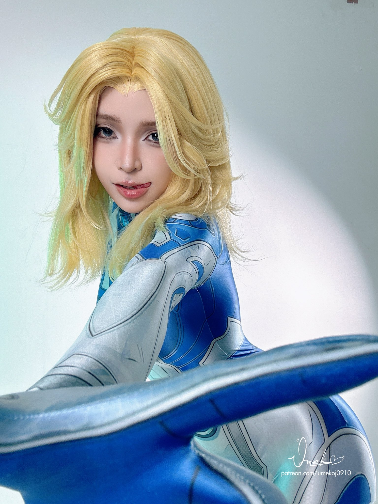 umeko j, umekojcosplayer, sue storm, fantastic four, marvel, marvel rivals, real life, cosplay photo, highres, photo (medium), 1girl, artist name, blonde hair, blue bodysuit, bodysuit, cosplay, female focus, licking lips, looking at viewer, multicolored bodysuit, solo, sue storm (cosplay), superhero costume, tongue, tongue out, two-tone bodysuit, watermark, white bodysuit