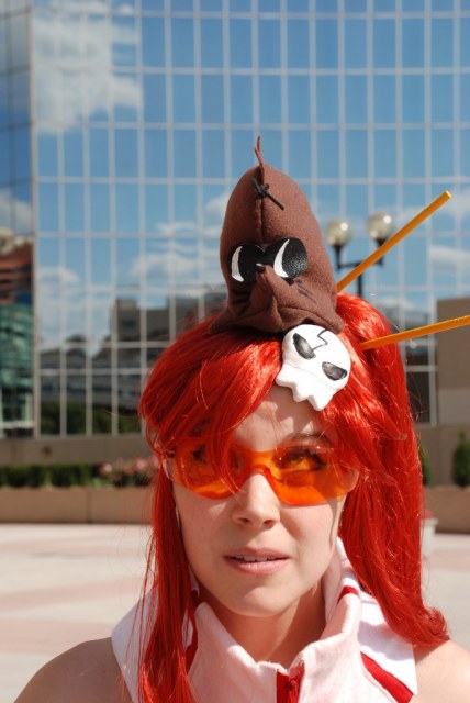 ellarcy, boota (ttgl), yoko littner, tengen toppa gurren lagann, visor, cosplay photo, photo (medium), 1girl, cosplay, face piercing, female focus, green eyes, nose piercing, nose stud, orange-tinted eyewear, orange-tinted glasses, piercing, ponytail, red hair, safety glasses, skull, solo, sunglasses, tinted eyewear, wig, yellow-tinted eyewear