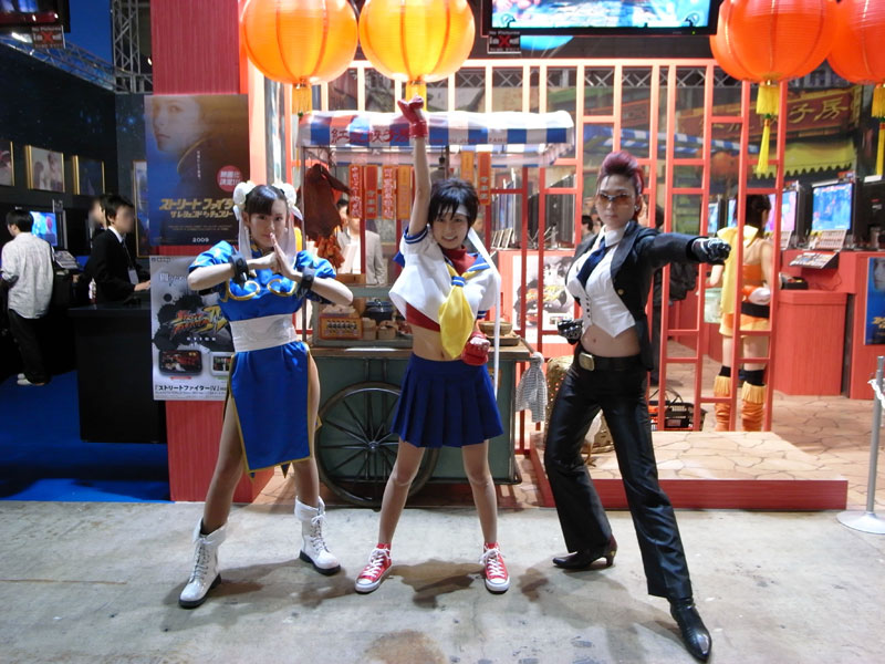 chun-li, crimson viper, kasugano sakura, capcom, real life, street fighter, street fighter iv (series), artist request, cosplay photo, photo (medium), 3girls, black hair, blue sailor collar, bracelet, braid, china dress, chinese clothes, chun-li (cosplay), cosplay, crimson viper (cosplay), dress, fingerless gloves, gloves, headband, jewelry, kasugano sakura (cosplay), long hair, multiple girls, pantyhose, pelvic curtain, pompadour, punching, red hair, sailor collar, school uniform, serafuku, shoes, short hair, spiked bracelet, spikes