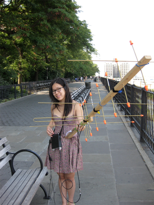 photo (medium), tagme, 1girl, antenna, asian, bench, day, dress, facing viewer, feet out of frame, female focus, glasses, legs together, looking at viewer, no socks, outdoors, railing, sleeveless, sleeveless dress, smile, solo, standing, sundress, tree