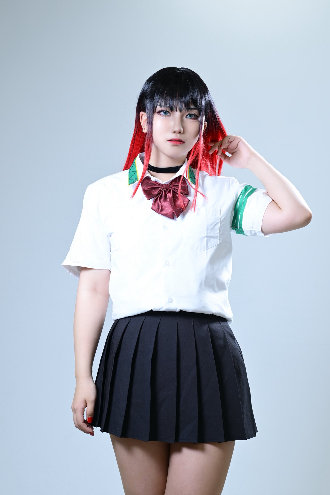 rrrrr0396, tsubakino tasuku, real life, wind breaker (nii satoru), commentary, cosplay photo, highres, photo (medium), 1boy, adjusting hair, androgynous, arm at side, armband, bare legs, black hair, black skirt, blue eyes, bow, collared shirt, cosplay, indoors, jacket, japanese (nationality), male focus, multicolored hair, pleated skirt, red bow, red hair, red lips, red nails, shadow, shirt, sidelocks, simple background, skirt, solo, straight hair, streaked hair, tsubakino tasuku (cosplay), unworn jacket, white background, white shirt