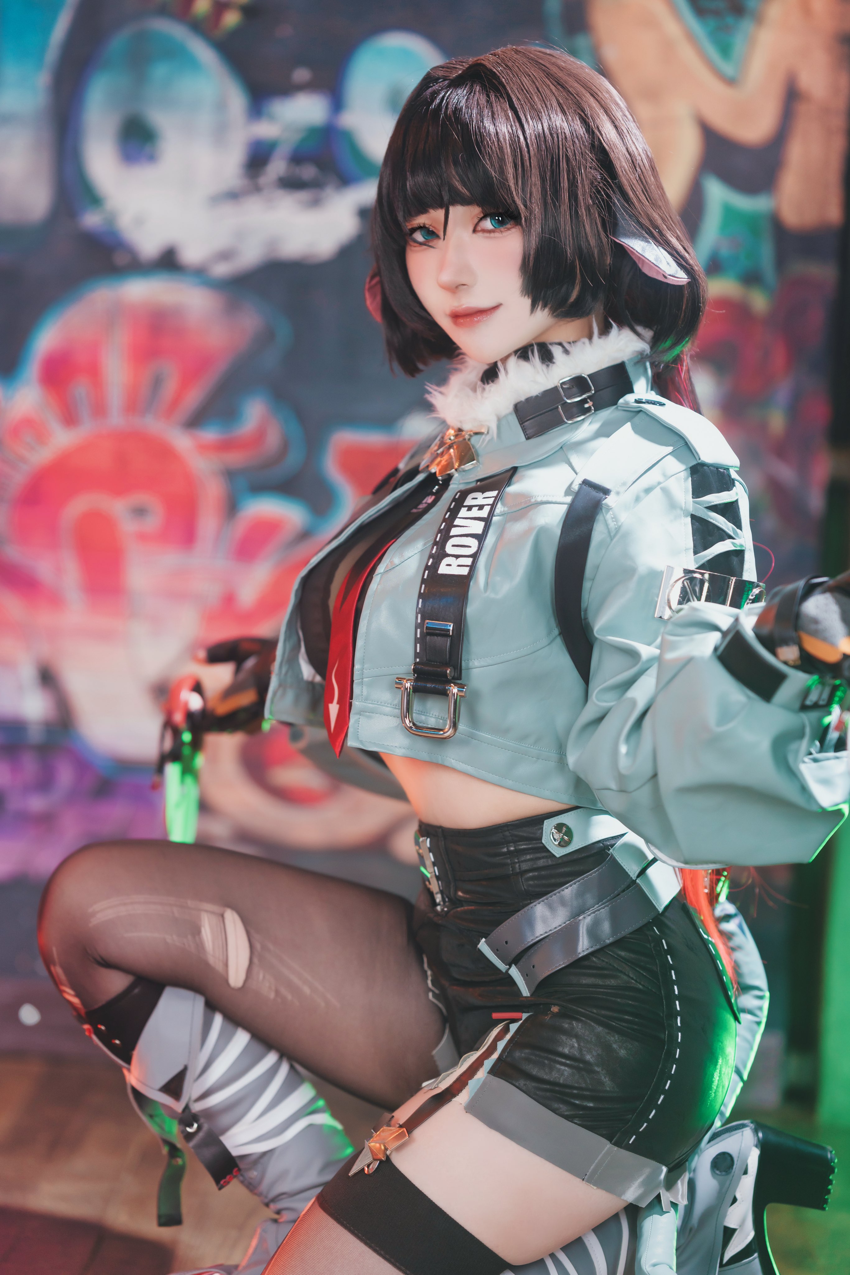 a erukun, jane doe (zenless zone zero), real life, zenless zone zero, absurdres, commentary, cosplay photo, highres, photo (medium), 1girl, 2024, animal ears, arms up, black gloves, black hair, black necktie, black shorts, blurry, blurry background, boots, brand name imitation, breasts, contrapposto, cosplay, crop top, depth of field, feet, feet out of frame, female focus, fingerless gloves, fingernails, from side, full body, fur-trimmed jacket, fur trim, garter straps, gloves, graffiti, green eyes, grey boots, grey jacket, grey thighhighs, indoors, jacket, jane doe (zenless zone zero) (cosplay), kneeling, knees up, lace trim, large breasts, light smile, long fingernails, long hair, long sleeves, looking at viewer, midriff, mouse ears, mouse girl, mouse tail, multicolored necktie, multiple views, necktie, pants, pantyhose, red lips, red necktie, selfie, shadow, sharp fingernails, sharp tail, shorts, skindentation, soles, tail, thick thighs, thighhighs, thighs, torn clothes, torn thighhighs, unworn pants, wide hips