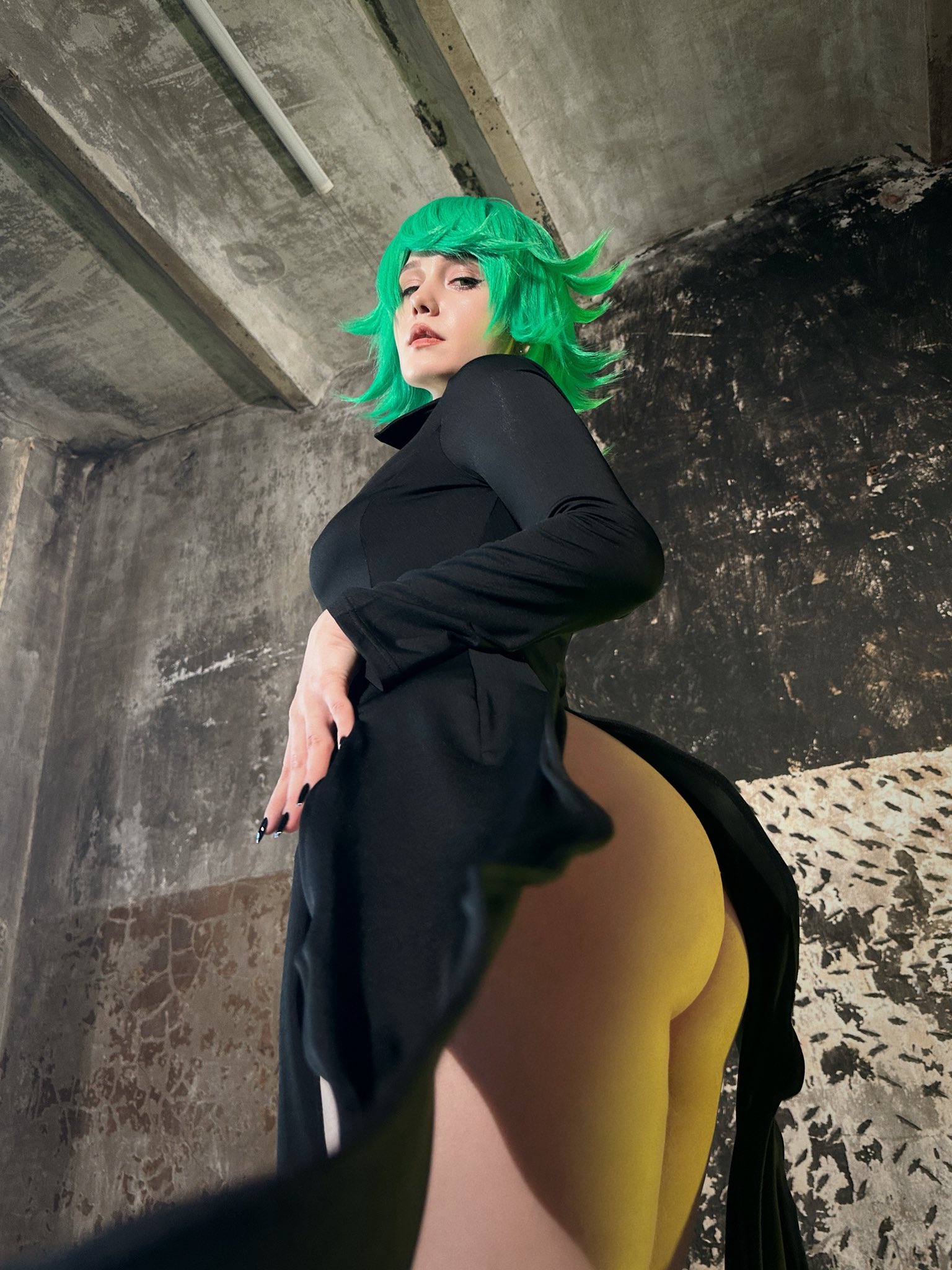 jyusan, tatsumaki, one-punch man, real life, highres, photo (medium), 1girl, ass, bare legs, black dress, breasts, closed mouth, cosplay, curly hair, dress, from below, green hair, lips, long sleeves, looking at viewer, looking back, short hair, standing, tatsumaki (cosplay), thighs